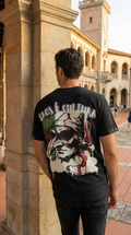 Person wearing a black t-shirt with a graphic design in an outdoor setting with columns and a clock tower.
