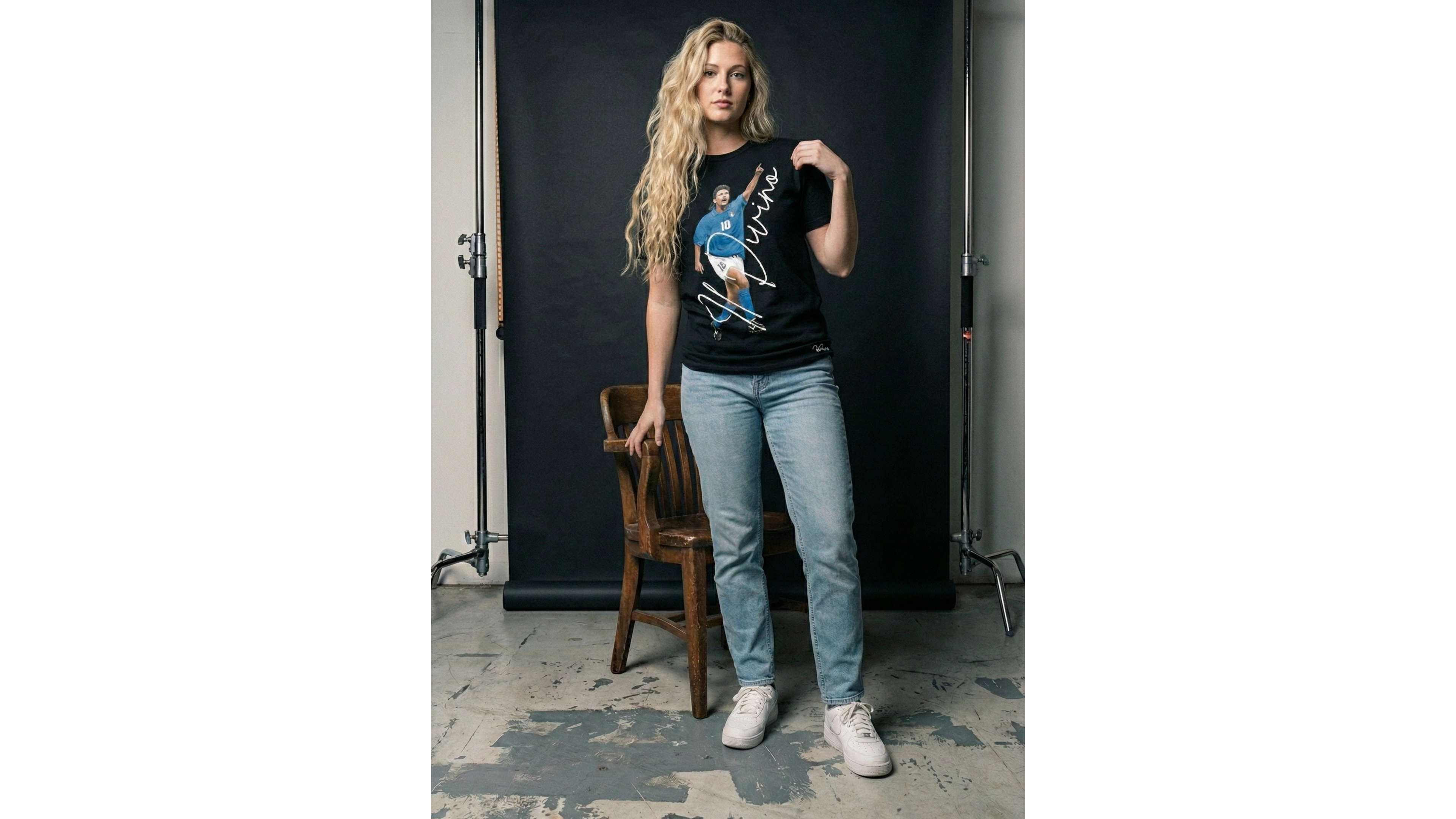 Person wearing a graphic t-shirt and jeans standing in a studio setting.